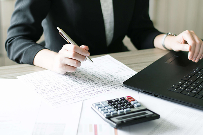 fechamento contábil - Pessoa verificando dados em uma mesa com uma calculadora e um notebook