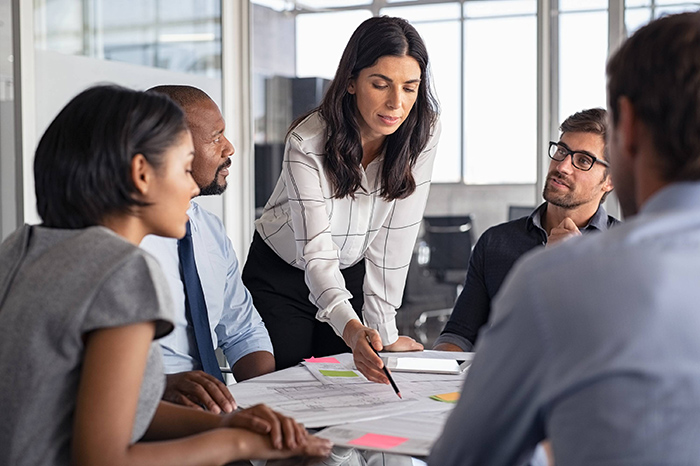 \"mapeamento mapeamento de mercado - equipe reunida em volta de uma mesa de escritório avaliando dados de mercado para encontrar oportunidades