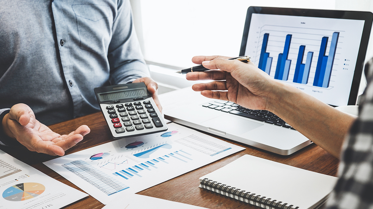 balanço patrimonial - duas pessoas avaliando custos e informações financeiras em um escritório utilizando calculadora e notebook