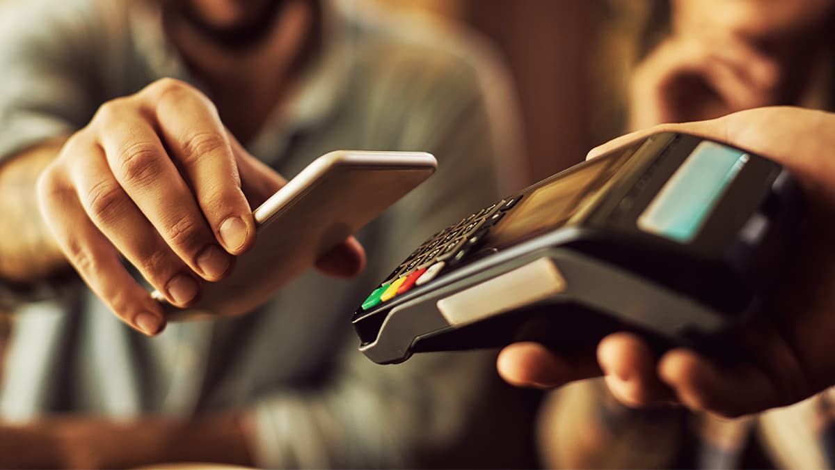 PDV - pessoa fazendo pagamento de uma compra através de aproximação do celular com a maquininha
