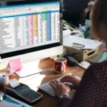 fluxo de caixa para distribuidoras - pessoa em frente a um computador com informações de custos na tela