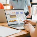 indicadores de desempenho- pessoas analisando KPIs em uma tela de notebook num ambiente de reuniões empresarial