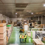 lead time na indústria moveleira - visão ampla do chão de fábrica de uma empresa que fabrica móveis onde funcionários caminham e há estoque de chapas de madeira máquinas industriais
