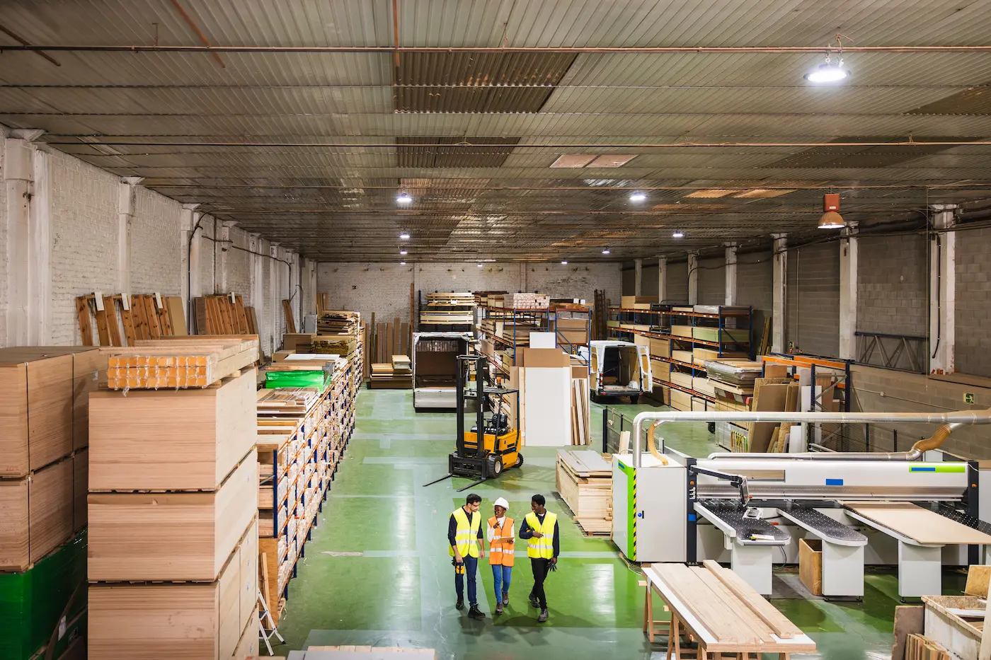 lead time na indústria moveleira - visão ampla do chão de fábrica de uma empresa que fabrica móveis onde funcionários caminham e há estoque de chapas de madeira máquinas industriais