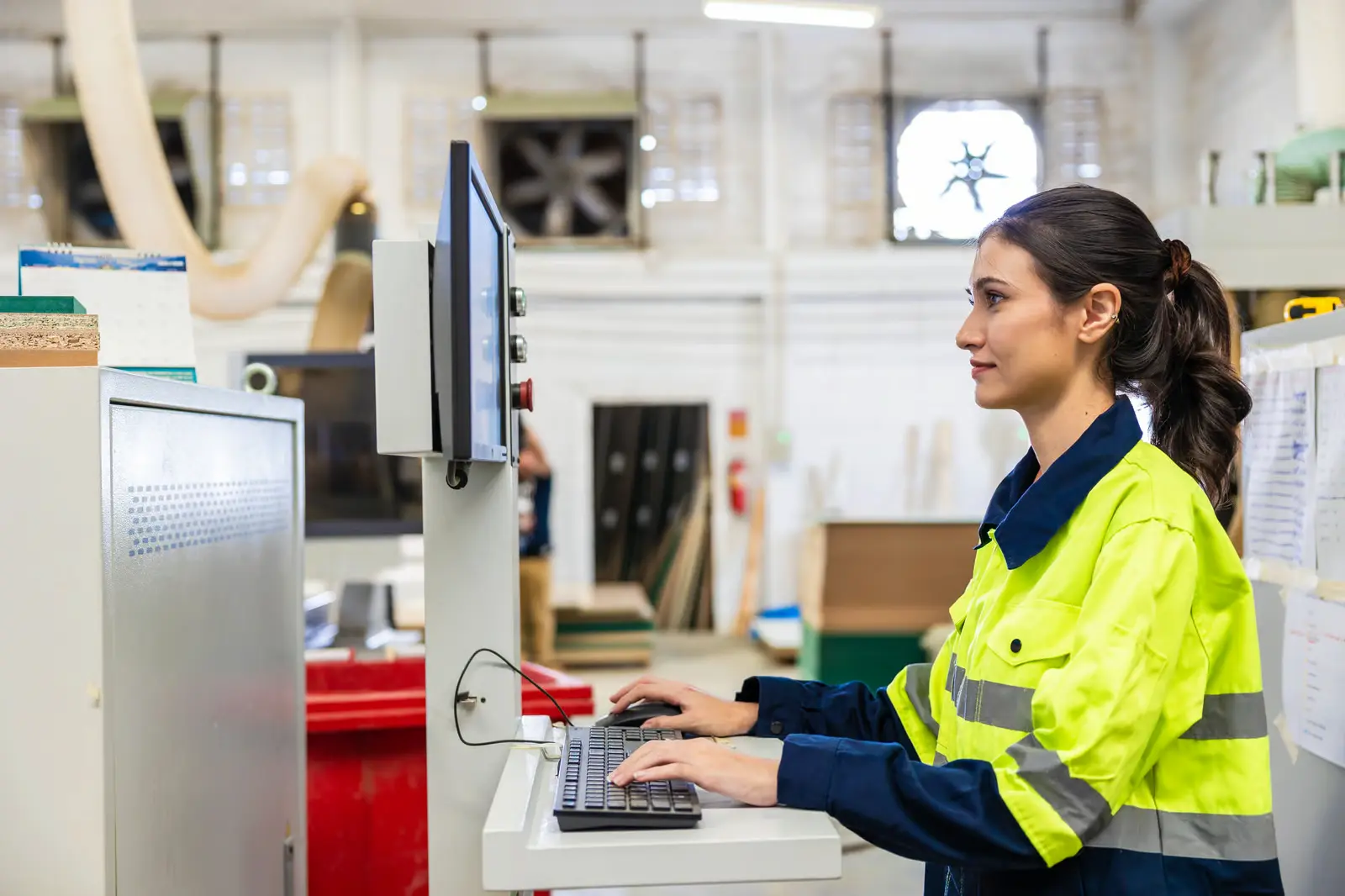 erp para fábrica de móveis - mulher operando software de equipamento em um ambiente fabril moveleiro